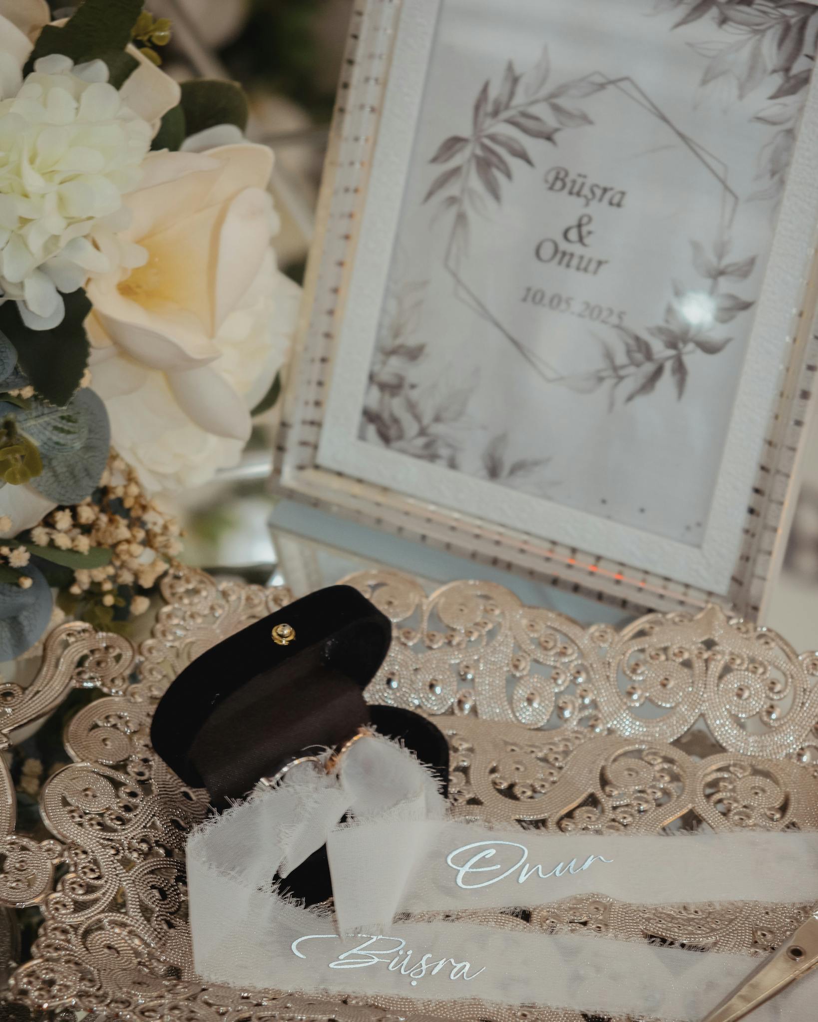 Beautiful wedding detail shot with elegant rings, flowers, and framed details.